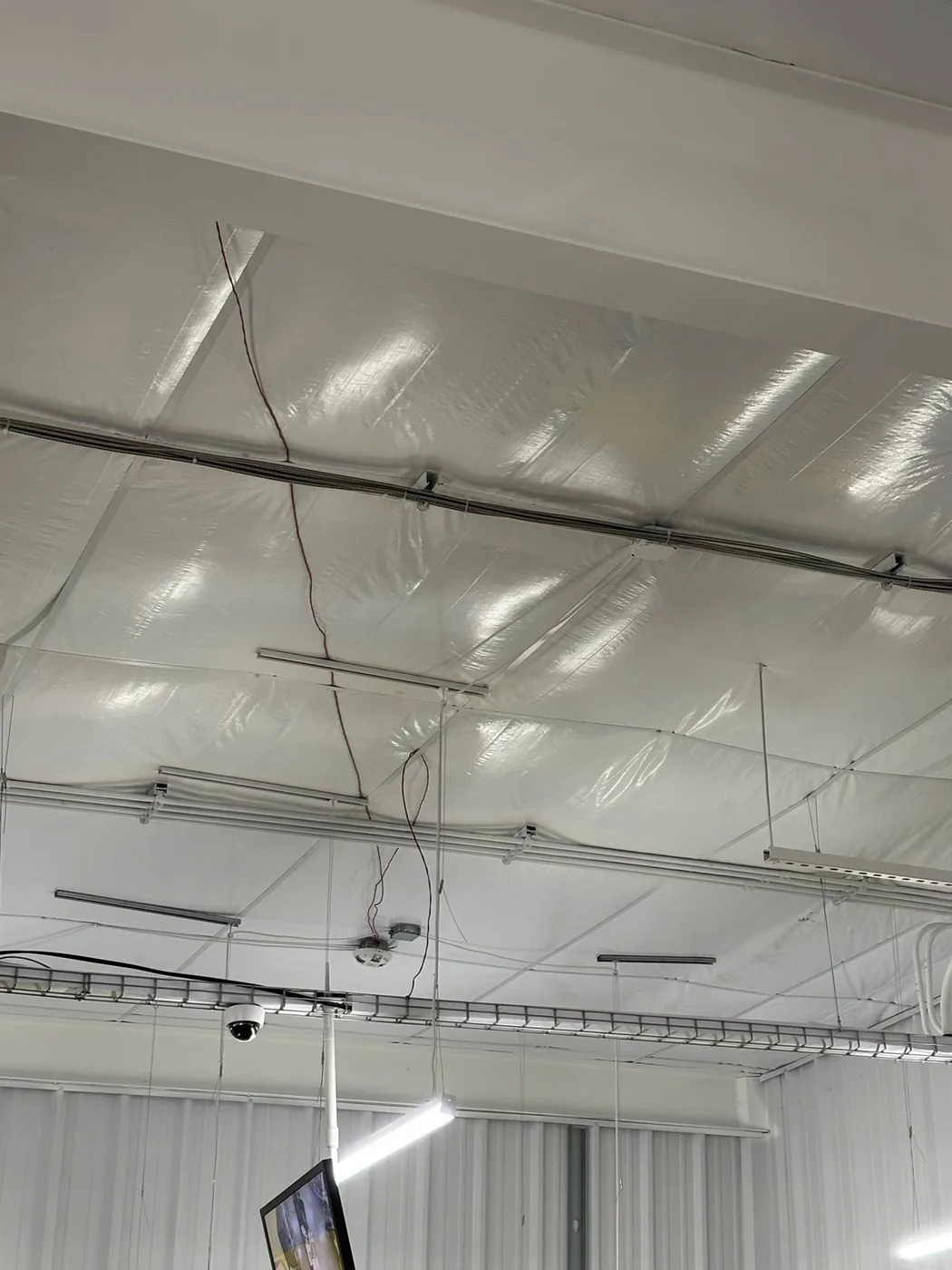 Conduit and wiring run across a metal-building ceiling